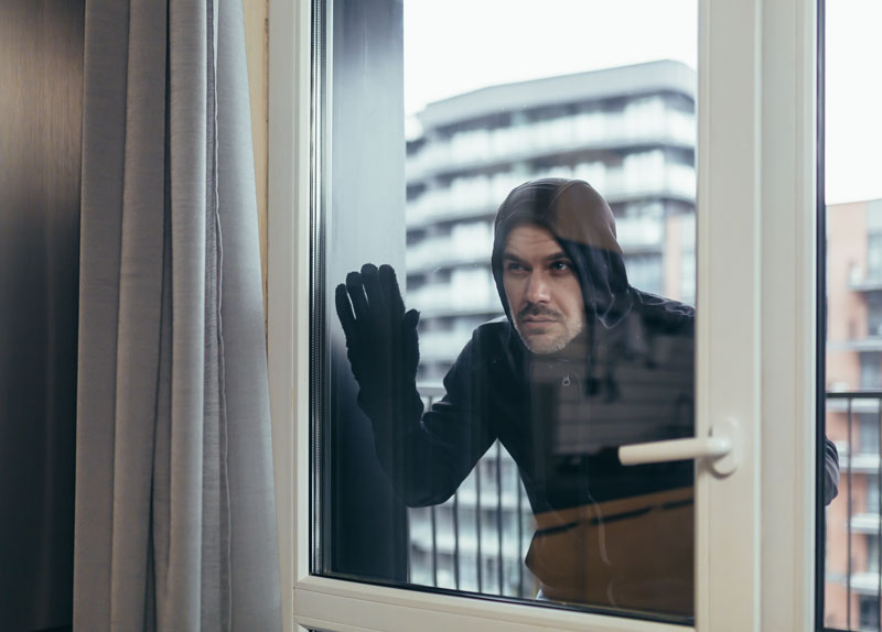 joven-ladron-ropa-oscura-mira-ventana-casa-apartamentos-quiere-entrar-vivienda